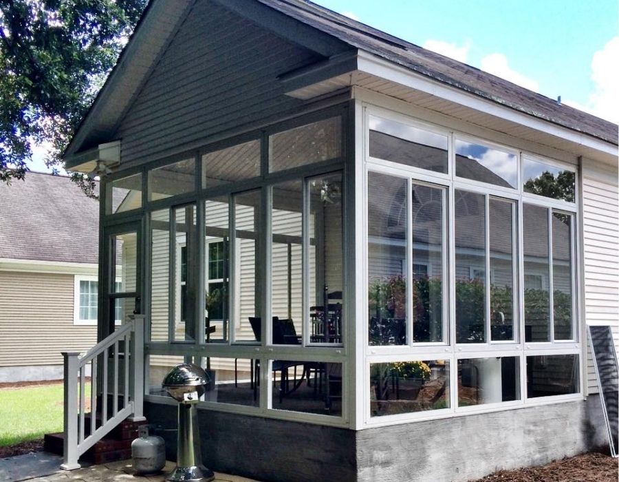 Sunroom with large, sparkling clean windows professionally serviced by 4 Seasons Window Cleaning in the Lowcountry, showcasing clear glass panels, white framing, and a bright, well-maintained exterior living space