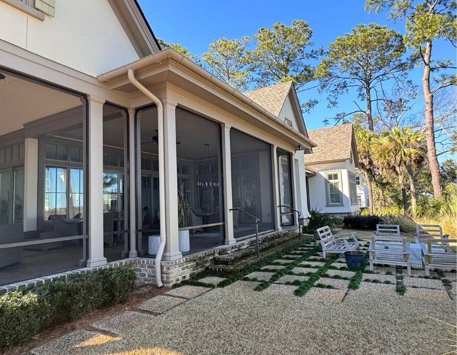 Lowcountry home with a screened-in porch and professionally installed seamless white gutters and downspouts by GutterXperts, enhancing outdoor living comfort and effective rainwater drainage